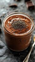 Creamy chocolate pudding topped with chia seeds in a glass jar on a rustic table setting photo