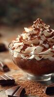 Creamy chocolate dessert topped with whipped cream and cocoa powder in a glass bowl displayed on a textured background photo