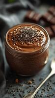 Chocolate mousse dessert decorated with seeds on a dark cloth with chocolate pieces nearby photo