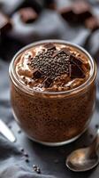 Delicious chocolate mousse topped with cacao nibs and dark chocolate pieces on a textured background photo