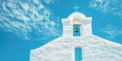 Whitewashed church with bell tower against a vibrant blue sky in a coastal village photo