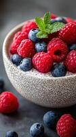 Fresh berries in a bowl with mint on a dark surface showcases vibrant colors and textures in a delightful arrangement photo