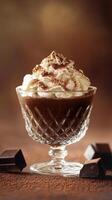 Creamy chocolate dessert topped with whipped cream and cocoa in a crystal cup on a textured background photo