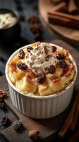 Creamy dessert topped with whipped cream and raisins served in a white ramekin on a rustic wooden table photo