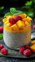 Tropical mango chia pudding topped with fresh raspberries and mint on a dark background photo
