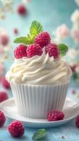 Delicious raspberry cupcake topped with whipped cream and mint leaves on a blue background photo