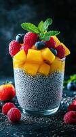 Colorful chia seed pudding topped with fresh fruits served in a clear glass on a dark background photo