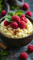 Creamy rice pudding topped with fresh raspberries and mint leaves served on a rustic table photo