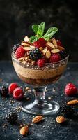 Delicious berry and almond dessert served in a glass bowl with a mint garnish on a dark textured background photo