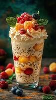 Colorful dessert with fresh fruit and whipped cream presented in a tall glass on a rustic wooden table photo