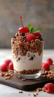 Delicious dessert featuring yogurt, granola, raspberries, and cherries in a clear glass photo