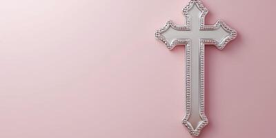 Decorative silver cross displayed on a soft pink wall for interior design and religious symbolism photo