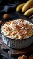 Creamy banana pudding topped with cookies in a rustic kitchen setting with fresh bananas nearby photo