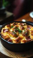 Delicious baked casserole with crispy topping and ham served in a cast iron skillet on a wooden table photo