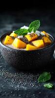 Delicious bowl of chia pudding topped with fresh mango and mint leaves in a dark setting photo