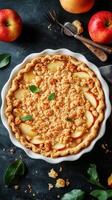 Warm apple crumble pie with fresh apples on a dark kitchen countertop photo
