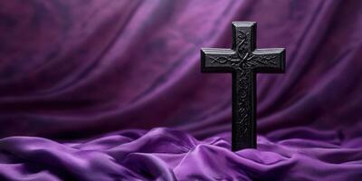 Black cross placed on lush purple fabric as a symbol of faith during a spiritual reflection moment photo