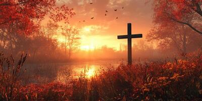 Sunset over serene lake with cross in foreground among autumn foliage and flying birds in peaceful nature setting photo