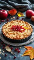 Freshly baked fruit crumble with apples and red currants displayed on a rustic table with autumn decorations photo