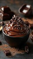 Rich chocolate mousse with chocolate shavings in a black bowl on a dark surface photo