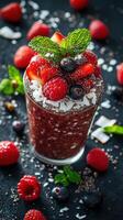 Fresh berry smoothie topped with mint on a black background featuring coconut flakes and assorted fruits photo