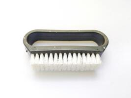 Closeup of a small, handheld brush with white bristles and a dark gray plastic handle. Perfect for illustrating cleaning, detail work, or the concept of meticulousness. photo