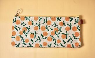 Pencil case with orange fruit fabric design isolated on horizontal brown cream background from top angle view. photo