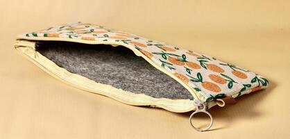 Empty opened pencil case with orange fruit fabric design isolated on horizontal brown cream background. photo
