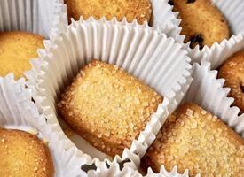 Close up yummy sugar coated butter cookies with white paper cups isolated on full frame horizontal background. photo