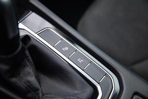 Buttons for activating the car's self-driving automatic autonomous parking function, parking assistant and parking sensors near the gear shift stick in a modern high-tech car photo