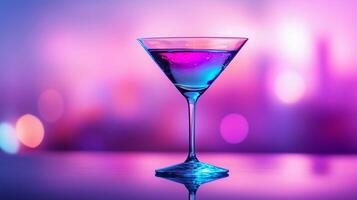 A blue martini glass with a blue liquid in it. The glass is on a table with a purple background photo