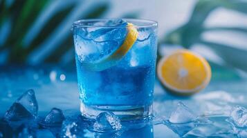 A glass of blue liquid with a lemon slice in it. The blue liquid is cold and refreshing photo