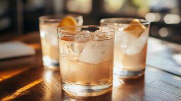 Three glasses of pink drink with ice cubes and lemon slices. The glasses are on a wooden table photo