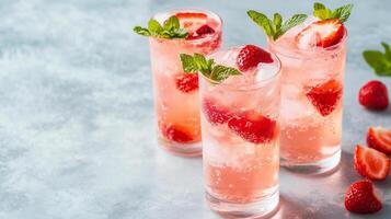 Three glasses of pink drink with strawberries and mint. The drink is served on a table. The drink is pink and has a minty flavor photo