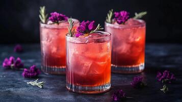 Three glasses of pink drink with purple flowers on top. The drink is served in a tall glass with ice photo