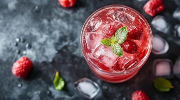 A glass of red drink with a garnish of mint leaves and raspberries. The drink is served in a tall glass and is topped with ice. The drink is garnished with a sprig of mint photo