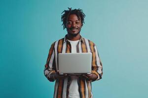 Happy man with laptop smiling in front of a light blue background, showcasing a moment of joy and success photo