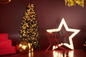 A blurry image in the New Year's decoration, the decor is done in red tones. Christmas tree in the interior in red and gold tones with space for copying photo