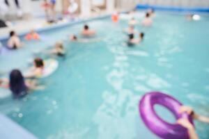 A close-up of a lilac inflatable ring floating in a pool, against a background of blurred people. With space to copy photo