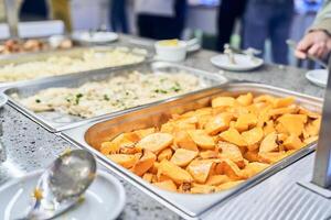 A buffet with metal containers with baked pumpkin and baked fish food. With space to copy photo