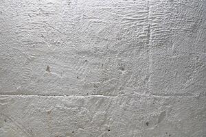 The grainy texture of a stone white wall. Uneven surface with space for copying photo