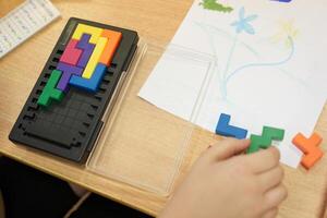 An unrecognizable child is playing a plastic-based puzzle game. Leisure time for children on vacation. With space to copy photo