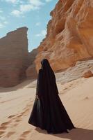 A woman in black robe walking through the desert photo