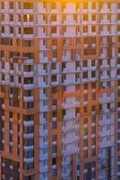 A building with many windows and a sun setting behind it photo