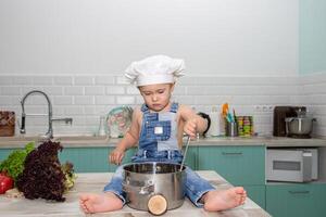A little boy in overalls and a chef hat cooking on a counter photo