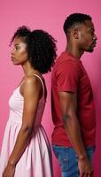 Portrait of a silent somber African American couple standing backtoback following a family argument on a pink studio background photo