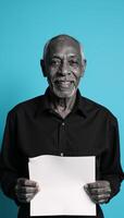 Elderly AfricanAmerican man with blank paper against solid blue backdrop photo