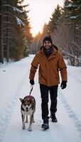 African American man and his dog walk through a snowy wintry forest at sunset amidst falling snow photo