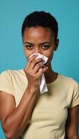Young AfricanAmerican woman depicted with discomfort as she blows her nose set against cool blue tones symbolizing winters chill focusing on the relatable struggles of fighting colds and allergies photo