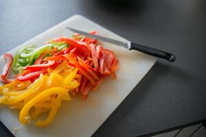 White cutting board with red, yellow and green paprika photo